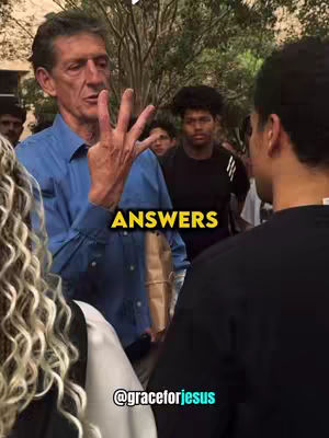 A man in a blue shirt is gesturing with his right hand with three fingers extended. The image has a crowd of people in the background. Text overlayed on the image reads "ANSWERS" in a yellow, filled rectangular box.