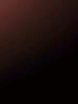 A dark, slightly blurred image featuring a gradient of colors, transitioning from a black base to a reddish-brown at the top. The image has a simple, abstract composition with no discernible subjects or objects.