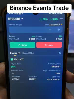 A smartphone screen displays the Binance Events Trade interface, with blue and green UI elements. The image is framed in portrait mode, held by a hand.