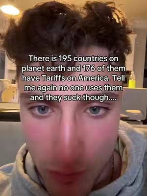 A selfie-style shot featuring a young man with dark, tousled hair and a light gray hoodie. The image is a close-up, with the man's face taking up most of the frame. Text is overlaid, providing context. The background is blurred.