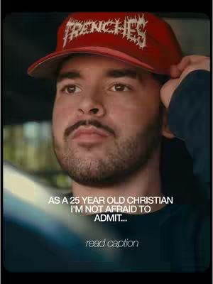 A man with a red baseball cap that says "FRENCHIES" in white, is looking to the side and touching the brim of his cap with his right hand. Text overlays appear over his chest, mentioning his age and willingness to admit things as a Christian. The background is blurred.