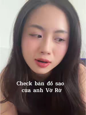 A close-up shot featuring a young Asian woman with long, dark hair. She has fair skin, rosy cheeks, and is wearing light makeup with a pink lip color. The background is minimally visible, suggesting she is indoors. Below the woman is a text overlay in Vietnamese.