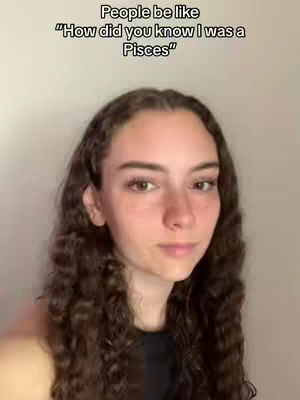 A woman with long curly brown hair looks towards the viewer, with the text overlayed at the top of her face. The background is a plain, neutral color.