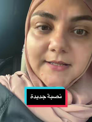 A close-up shot of a woman in a hijab. She is looking slightly to the side with a subtle smile. A text overlay, inside a frame, appears at the bottom of the frame. The background is a car interior, suggested by the seat.