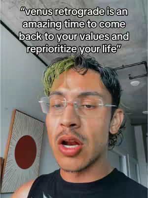 A man with a serious expression speaks directly at the camera. The background includes a painting and part of a room. Text overlayed on the video states, "venus retrograde is an amazing time to come back to your values and reprioritize your life."