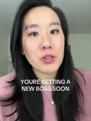A medium shot features a woman with long black hair and a pink top, speaking directly into the camera. Text overlayed on the image reads, "YOU'RE GETTING A NEW BOSS SOON". The woman is centered with a soft background.