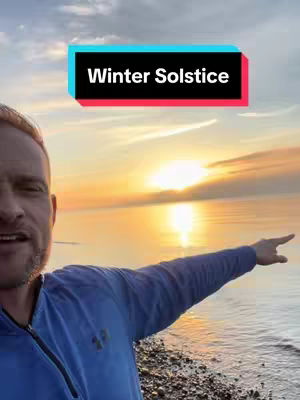A man stands near a beach at sunset, pointing towards the horizon. A text overlay reads "Winter Solstice". The sky is a mix of colors including orange and blue.