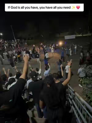 A night time shot of a crowd of people raising their hands in a worship situation in a park. There are lights in the background and the words 'If God is all you have, you have all you need' with a heart symbol.