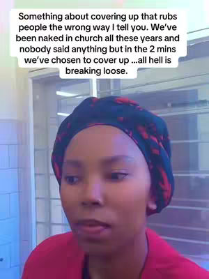 A woman with a dark head covering speaks to the camera. Text overlay appears above her head.