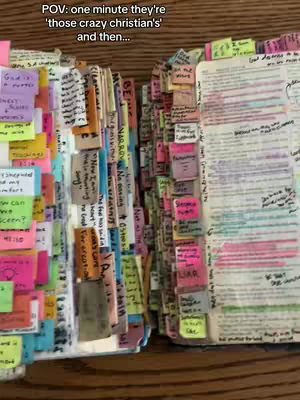 Two open books are displayed, filled with colorful sticky notes and handwritten notes. The pages are heavily annotated with various colors of ink, highlighting the text. The background is a wooden surface.