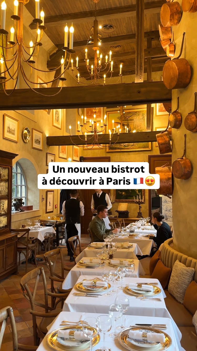 The cover image shows the interior of a warmly lit restaurant with tables set for dining. The decor includes vintage-style chandeliers, and framed art pieces adorn the walls. A text overlay, highlights the restaurant name 'Un nouveau bistrot à découvrir à Paris', with a French flag and heart emojis. People are seated at tables, suggesting a dining scene.