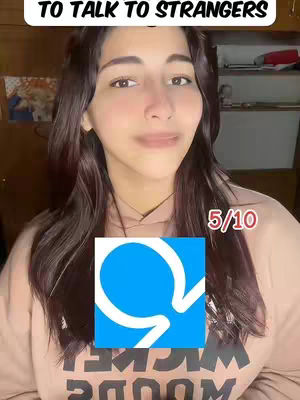 A woman with long, dark hair looks directly at the camera, slightly smiling. The frame is from the chest up. Overlaying her chest is a vibrant blue and white logo with a score, and text is above her head.