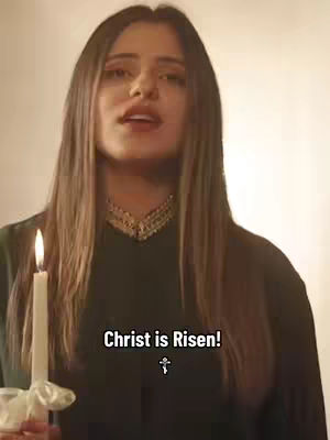 A woman holding a candle with a white background. Text overlays state 'Christ is Risen!'