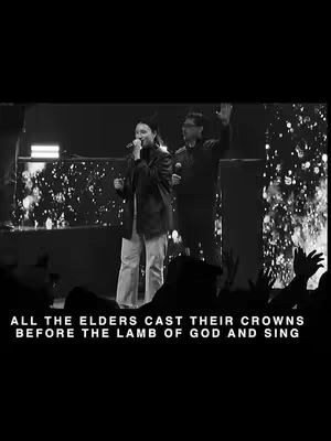 A black and white photo captures a live music performance. A woman with long hair and the man are at right in front. A spotlight shines on them. Text is written below in a white font.