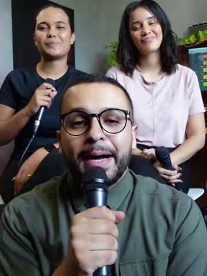 The cover image shows three people, two women seated and one man in the foreground. The man in the foreground is holding a microphone. The background is blurred. The two women are in the background and both have microphones. The color palette is natural; composed of greens for some of the backdrop and clothing and black clothing for two people.