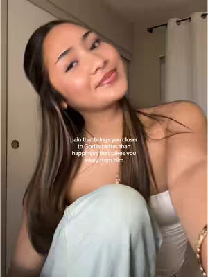 A young woman with long, highlighted hair smiles gently, looking slightly up and to the side. She is wearing a white top, and some pale green pants. Text is overlaid on the image.