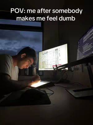 A dimly lit scene shows a person at a desk illuminated by a bright light. The text overlay reads 'POV: me after somebody makes me feel dumb'.