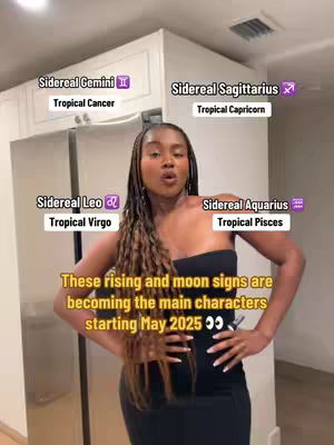 A woman stands in a kitchen looking at the camera. Text overlays indicate astrological themes. She is wearing a black top and has long braided hair.