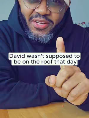 A close-up shot features a man with a beard and glasses, pointing his index finger upwards. A text overlay at the bottom reads: 'David wasn't supposed to be on the roof that day'. The composition is tightly framed, focusing on the man's face and gesture.