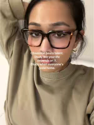 A selfie-style image featuring a woman with dark hair and glasses, angled slightly upwards. She is wearing large, square-framed glasses with a brown and black pattern. Her expression is neutral, and the background is soft, with the upper part of a light-colored sweater visible. Overlayed text provides motivational tips.