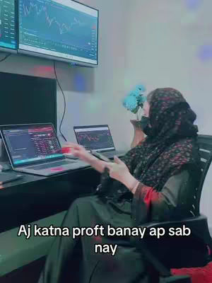A woman in a headscarf sits at a desk with multiple screens displaying trading charts. She gestures towards the screens, with text overlaid at the bottom asking about profit.