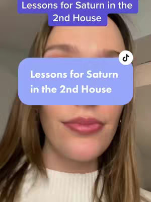 A close-up shot of a woman's face with a text overlay. The woman has light skin, light brown hair, and is wearing a white shirt. Two text boxes, stacked on top of each other, are placed in front of her face, with 'Lessons for Saturn in the 2nd House' in the bottom box.