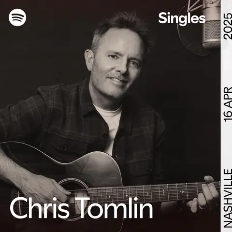 A black and white photo features a man with short hair playing an acoustic guitar. Spotify and Singles branding are in the top left and right corners, and the artist's name, Chris Tomlin, is at the bottom.