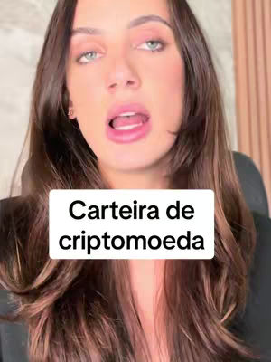 A selfie-style shot featuring a woman with long, brown hair and fair skin, looking directly at the camera with an open mouth. A white rectangular box with the text "Carteira de criptomoeda" (Cryptocurrency Wallet) is superimposed over her. The background is slightly blurred.