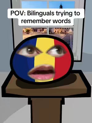 A cartoonish image featuring a face constructed from a stylized flag pattern, evoking a humorous or relatable expression. The face is centrally positioned in a circular shape. Above the head is a white box displaying the text "POV: Bilinguals trying to remember words". The background includes a window with a view of an evening cityscape, providing context to the scene.