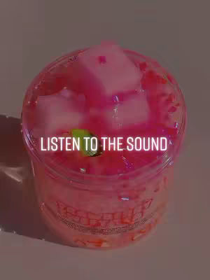 A clear plastic cup filled with a pink, viscous substance, likely slime or a similar material, topped with large, pale pink cubes that resemble marshmallows. The substance has small, glistening embellishments scattered throughout. Overlaid in the image is the text 'LISTEN TO THE SOUND'.