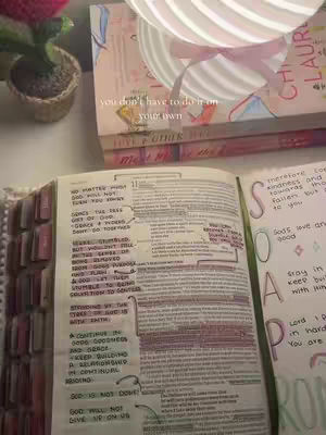 The cover image shows an open book on a desk, with text highlighted. A small potted plant is visible on the left side. Behind it, there are two stacked books and a lamp in the background, and a pink flower. The overall setting gives the impression of a study or workspace.