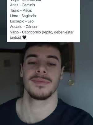 A selfie-style shot featuring a man from the chest up, smiling slightly with a light beard and mustache. Behind him, a text overlay shows astrological signs and their compatibility, framed in a vertical list. The background includes hints of a room, with soft neutral tones.