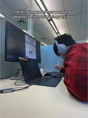 A person wearing headphones, and a red-and-black flannel shirt is working on a desk. A laptop, a monitor, and a tablet are showing on the desk. The overlay text over the person says, "me thinking about how people did degrees before technology existed".