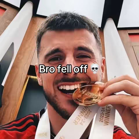 A close-up shot of a smiling man holding a gold medal in his teeth, with the text overlayed.