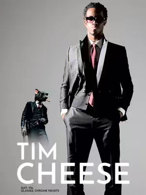 The cover image features a fashion-style illustration. A man in a modern black suit with sunglasses is standing tall on the right side. Behind him and to the left, a business-suited mouse with sunglasses and a cigar is positioned. The title 'TIM CHEESE' is in bold, white font at the image’s base. The overall composition has a studio-shot look, with a gradient backdrop.