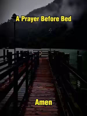 A serene, dark-toned image of a wooden pier extending into a body of water, possibly a lake or ocean, with a mountainous, tree-covered background. The sky is overcast. Text overlays in yellow, 'A Prayer Before Bed' and 'Amen', are prominently displayed.