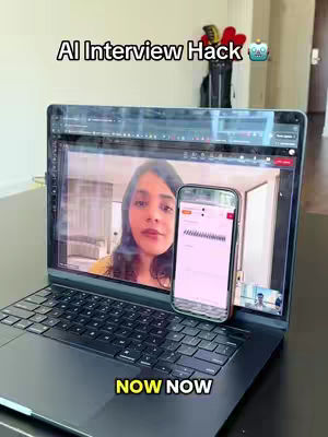 The image shows a person using a laptop. The laptop screen displays a video of a woman in a video call, with a mobile phone resting on the laptop. Overlaid text reads, “AI Interview Hack”. The background includes a black bag with items, some red hearts. The phone displays an interface with a data graph, and another person in the bottom right corner. At the bottom, the text “NOW NOW” is present.