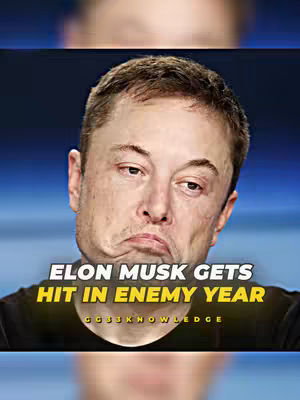 The cover image is a close-up shot of Elon Musk, the CEO of Tesla. He is looking slightly downwards with a somewhat quizzical or unhappy expression. Above Elon Musk is a blurry blue background, and the bottom portion of the image shows a blurry, dark area, likely the subjects clothing.. Overlaying the central part of the image is a text overlay with the title/hook: “ELON MUSK GETS HIT IN ENEMY YEAR” with the name of the account in a smaller font