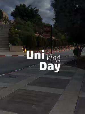 An outdoor campus scene with a road in the foreground and a sign post with arrows pointing towards a direction. Text overlay, "Uni Vlog Day" is placed on top of the image.