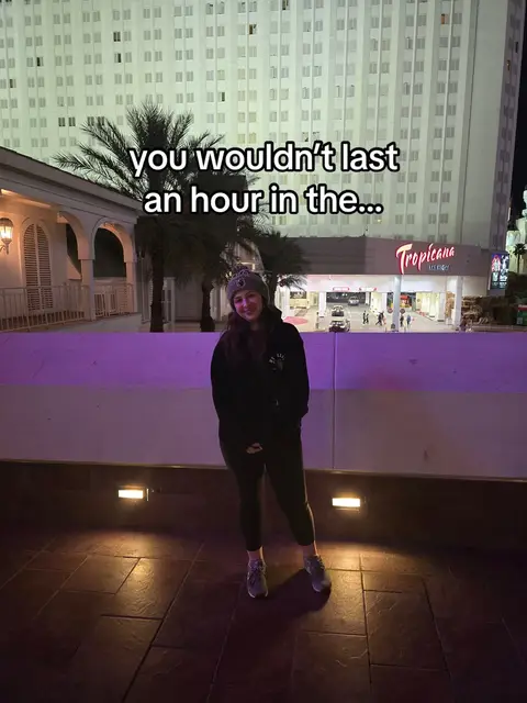 A woman stands in front of the Tropicana sign at night. The image is framed from the waist up, with the woman in the foreground and a large building in the background. The text overlay is set against the backdrop of the building and adds a light-hearted or humorous tone to the scene.