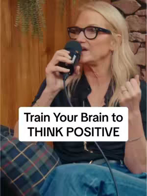 A woman with blonde hair and glasses is holding a microphone. The words "Train Your Brain to THINK POSITIVE" are overlaid on the bottom.