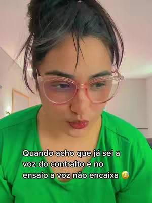 A woman wearing glasses and a green shirt looks down with pursed lips, text overlayed on the bottom. The background is a blurred interior.