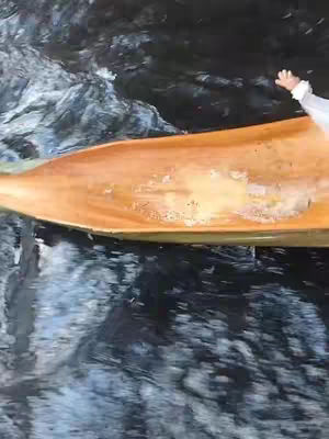 The cover image shows a portion of a wooden boat or paddle viewed from a low angle, with water in the background. The boat is a warm, light brown color, contrasted by the darker, more reflective water. The water's surface has ripples and waves, indicating movement. The image is slightly blurred.