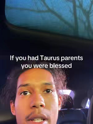 A selfie-style video with a man in the foreground. The lighting appears to be natural and soft, possibly from an overhead source. Above the man's head, a dark area with a blurred texture transitions into a blue-toned area, likely a window or sky. The background behind the man is indistinct, suggesting a vehicle interior. The text overlayed on the image states 'If you had Taurus parents you were blessed.'