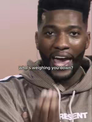 A close-up shot of a man with a short haircut and beard, wearing a patterned hoodie. The background is a solid, soft pink. Text overlayed on the image reads, 'who's weighing you down?'