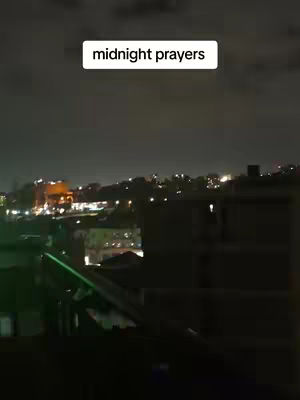 Nighttime cityscape view with lights, with a rectangular white text box containing the words 'midnight prayers'