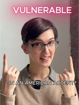 A woman with short dark hair and glasses points two index fingers up, smiling at the camera. Text overlays include \"VULNERABLE\" in a pink glow and \"IN AN AMERICAN ACCENT?\" in white text.