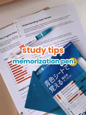 An overhead shot of study supplies including worksheets with red highlighted text, a pen, and a blue package. The text overlay reads 'study tips memorization pen' in a warm color palette.