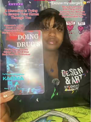 A woman with dark hair and dark top, holds up a card to the camera, with additional text overlays on the cover and background.