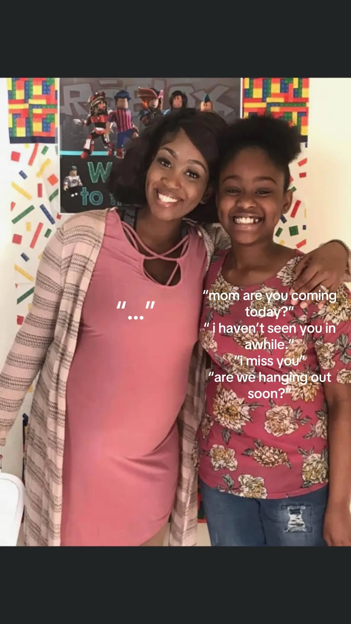 The image captures a close-up of two smiling women, one slightly pregnant, against a backdrop of a colorful wall. The woman on the left is wearing a pink dress and a striped cardigan, while the other is in a floral top and jeans. Above them is a Roblox-themed poster.